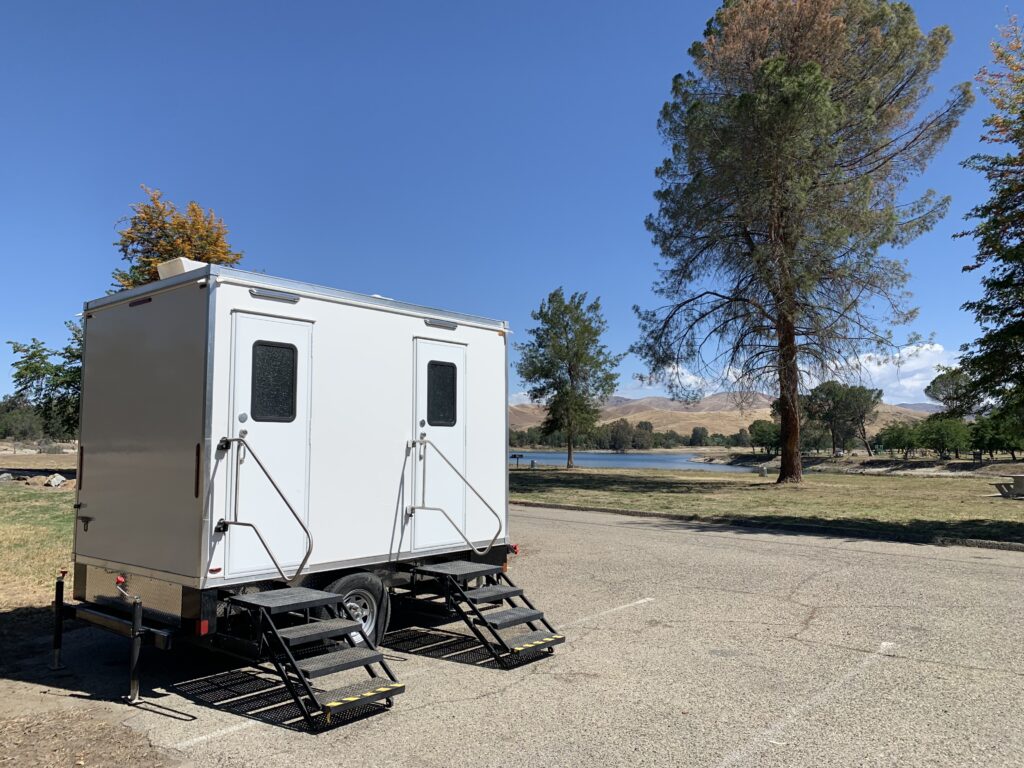 Bathroom trailer with two doors and steps in a lakeside parking lot, The Lavatory Los Angeles