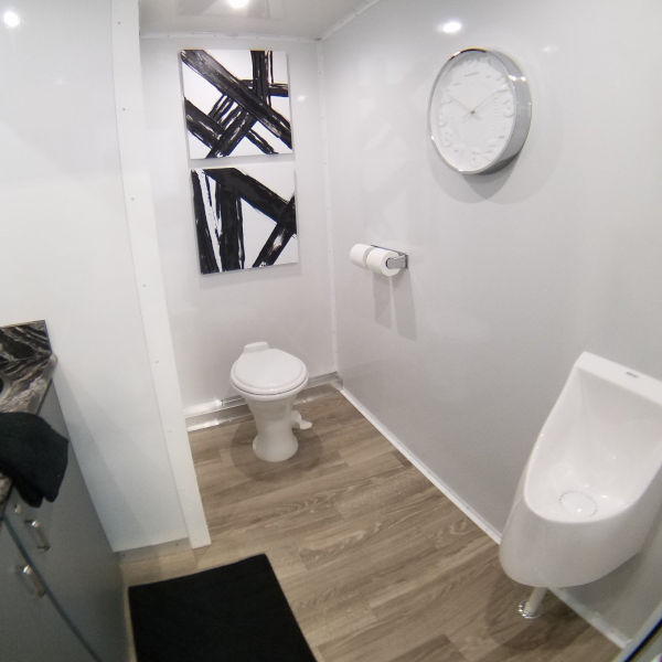 Bathroom trailer room with toilet, urinal, wall clock and black and white art, The Lavatory Los Angeles