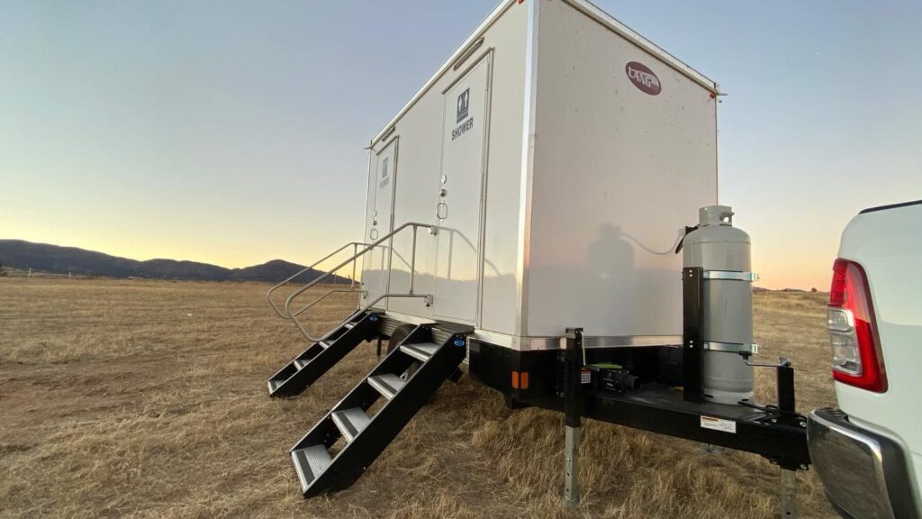 2-station private shower trailer with steps in a dry field at sunset, The Lavatory Los Angeles