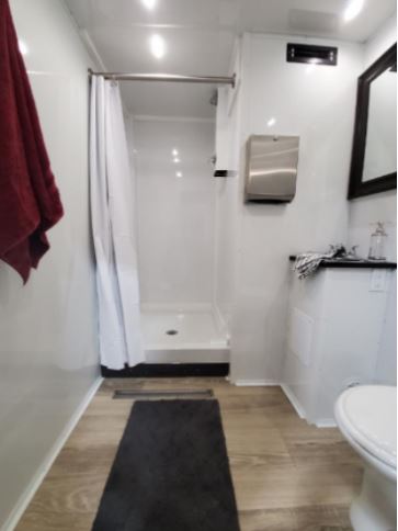 Shower stall with curtain, vanity and red towel inside a 2-station shower trailer, The Lavatory Los Angeles