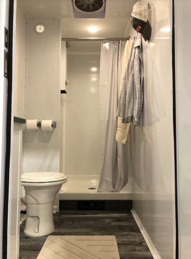 Private room inside a 4-station combo trailer with a shower stall, curtain, toilet and bath mat, The Lavatory Los Angeles