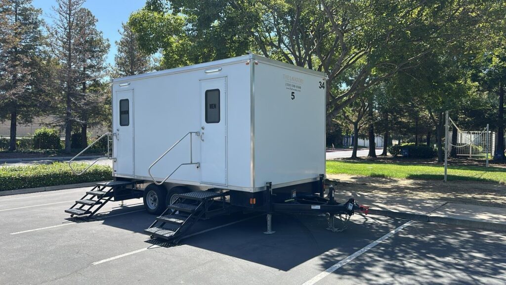 5-station private bathroom trailer parked in an office lot under shade trees, The Lavatory Los Angeles