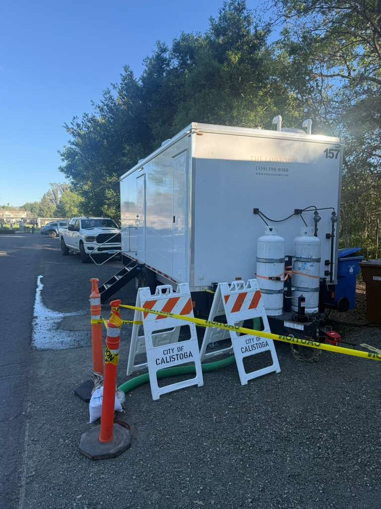 8-station laundry trailer behind city barricades and caution tape during a town water outage, The Lavatory Los Angeles