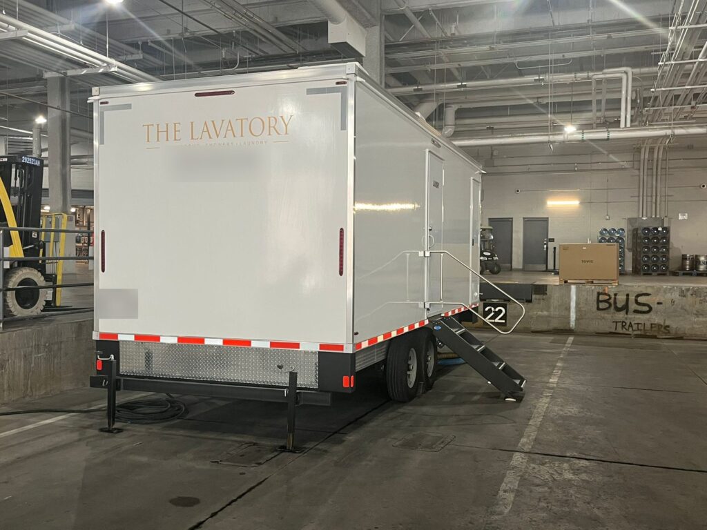 8-station laundry trailer parked indoors at a warehouse loading dock with its steps down, The Lavatory Los Angeles