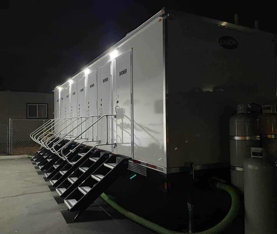 8-station shower trailer lit at night with propane tanks and steps at every door, The Lavatory Los Angeles