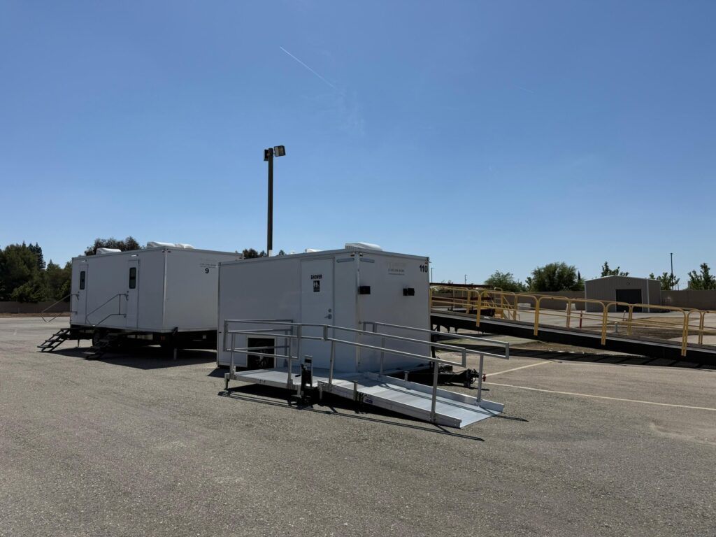 Accessible combo trailer with a ramp beside a bathroom trailer on a paved lot for a community car show, The Lavatory Los Angeles