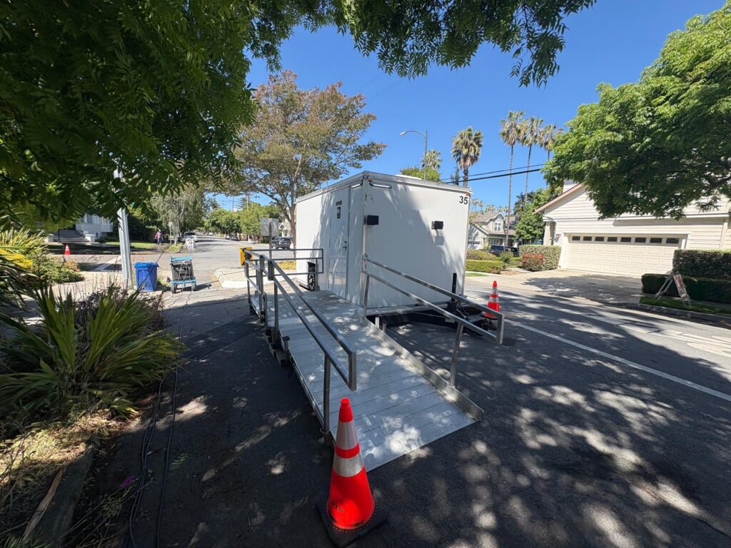 Accessible combo trailer with a railed ramp and traffic cones on a residential street for a film production, The Lavatory Los Angeles