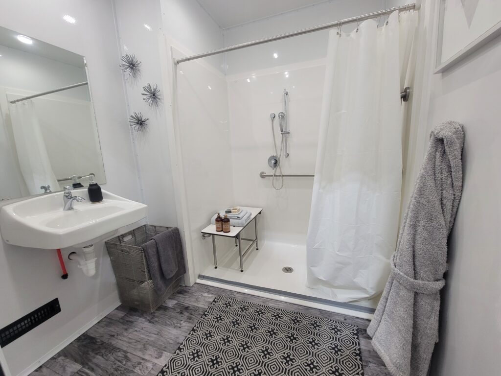 ADA shower room with roll-in shower, wall sink, bench and robe inside a shower trailer, The Lavatory Los Angeles