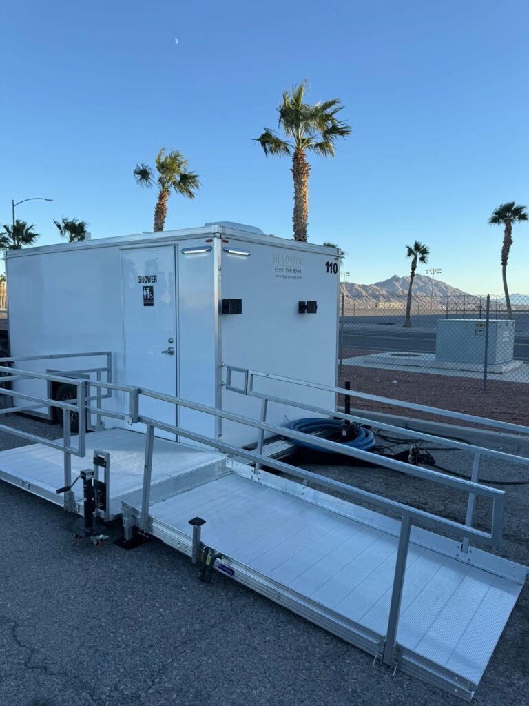 ADA plus 2 shower trailer with a railed ramp set up under palm trees and a clear blue sky, The Lavatory Los Angeles