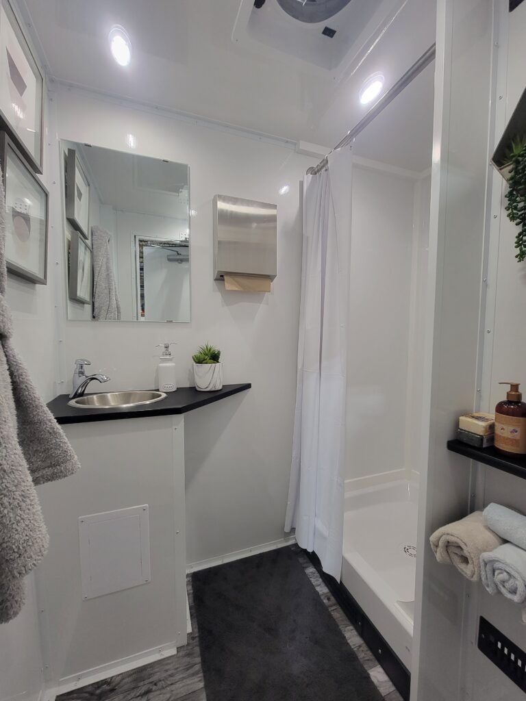 Overhead view of a shower room vanity, sink and mirror inside an ADA shower trailer, The Lavatory Los Angeles