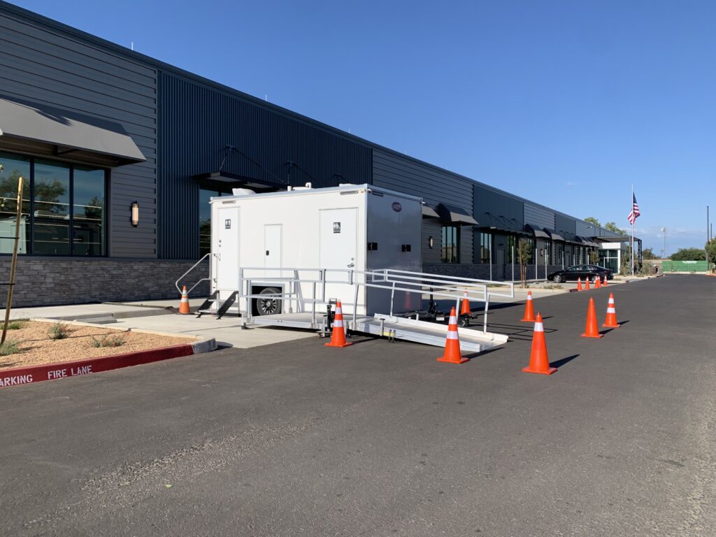 ADA plus 2 bathroom trailer with ramp and traffic cones outside an office building, The Lavatory Los Angeles