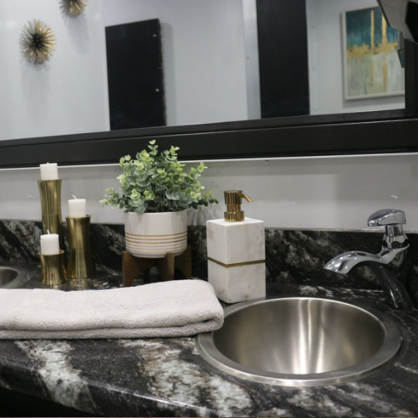 Close up of a granite vanity with round steel sink, candles and potted plant in a bathroom trailer, The Lavatory Los Angeles
