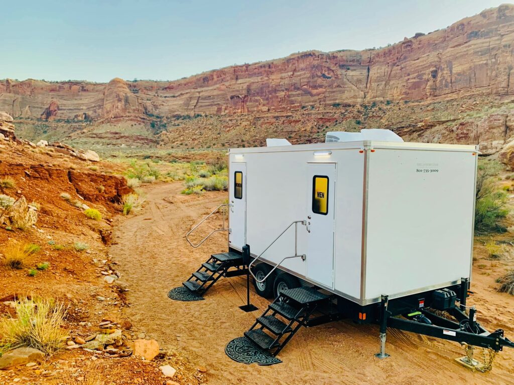 Portable bathroom trailer set on a dirt trail in a red rock desert canyon for a remote job, The Lavatory Los Angeles