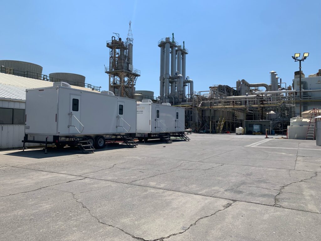 Row of bathroom trailers parked in a paved yard at an industrial plant, The Lavatory Los Angeles