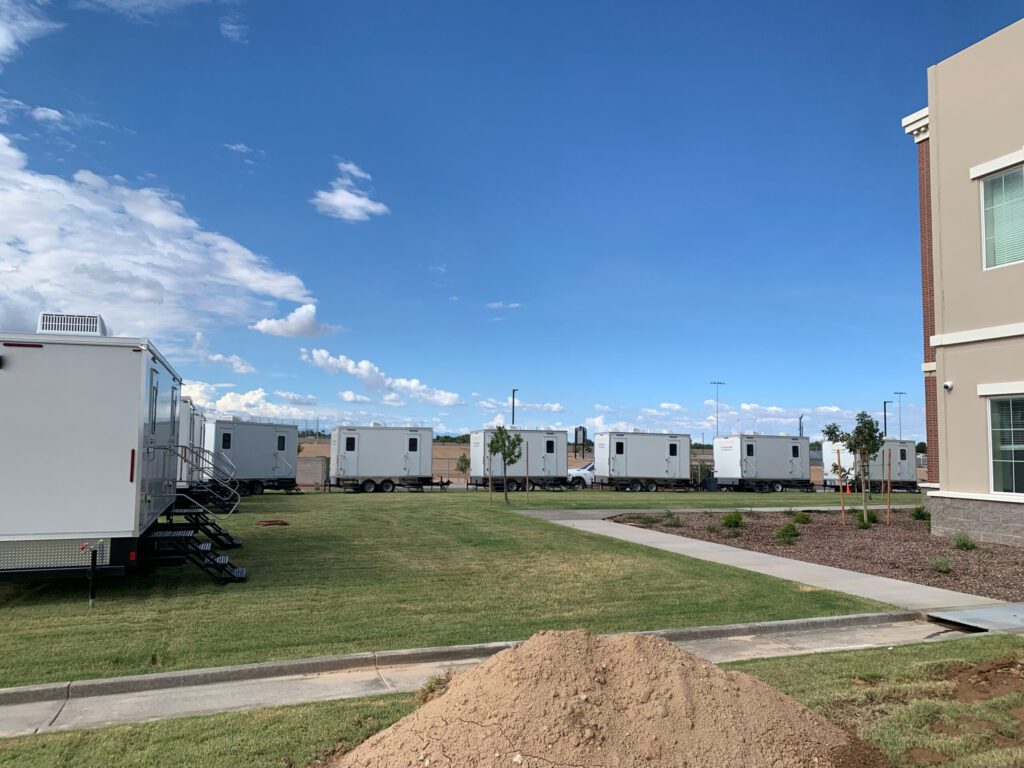 Row of luxury bathroom trailers lined up on a campus lawn for a large rental, The Lavatory Los Angeles