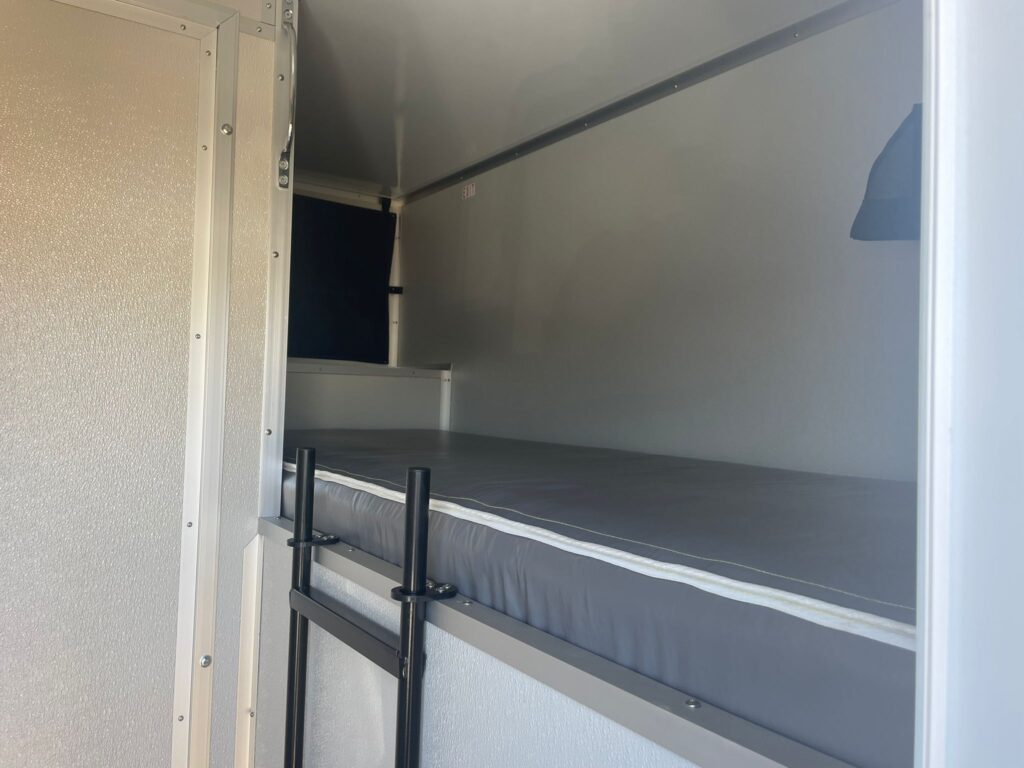 Padded sleeping bunk with a built-in ladder inside a 12-station bunkhouse sleeper trailer, The Lavatory Los Angeles