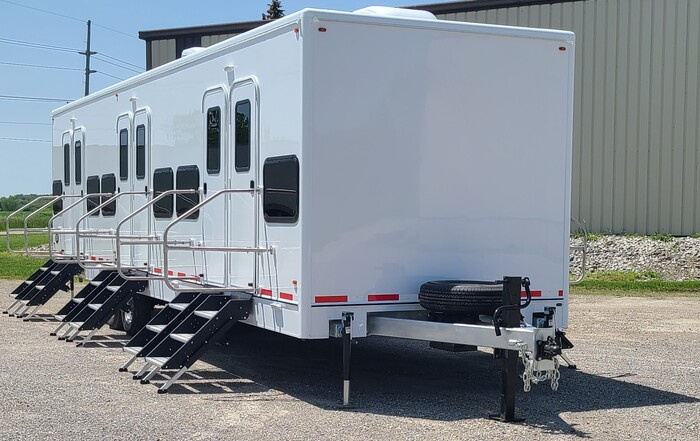 Front view of a bunkhouse sleeper trailer with multiple entry doors, windows and steps, The Lavatory Los Angeles