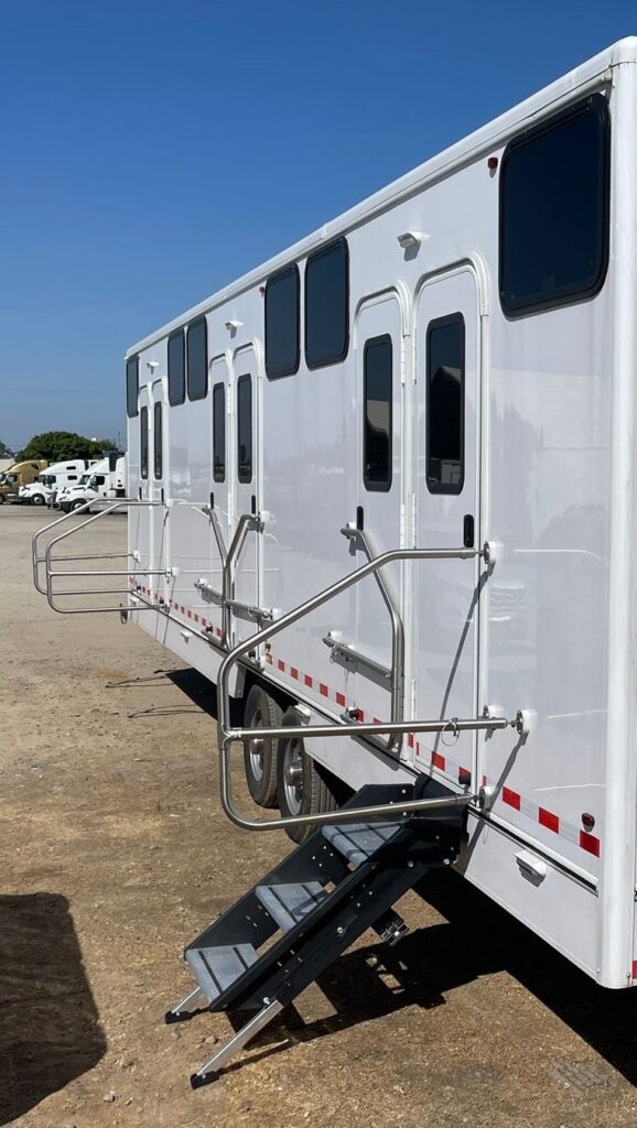 Side of a 12-station bunkhouse sleeper trailer with bunk doors, windows, handrails and fold-down steps, The Lavatory Los Angeles