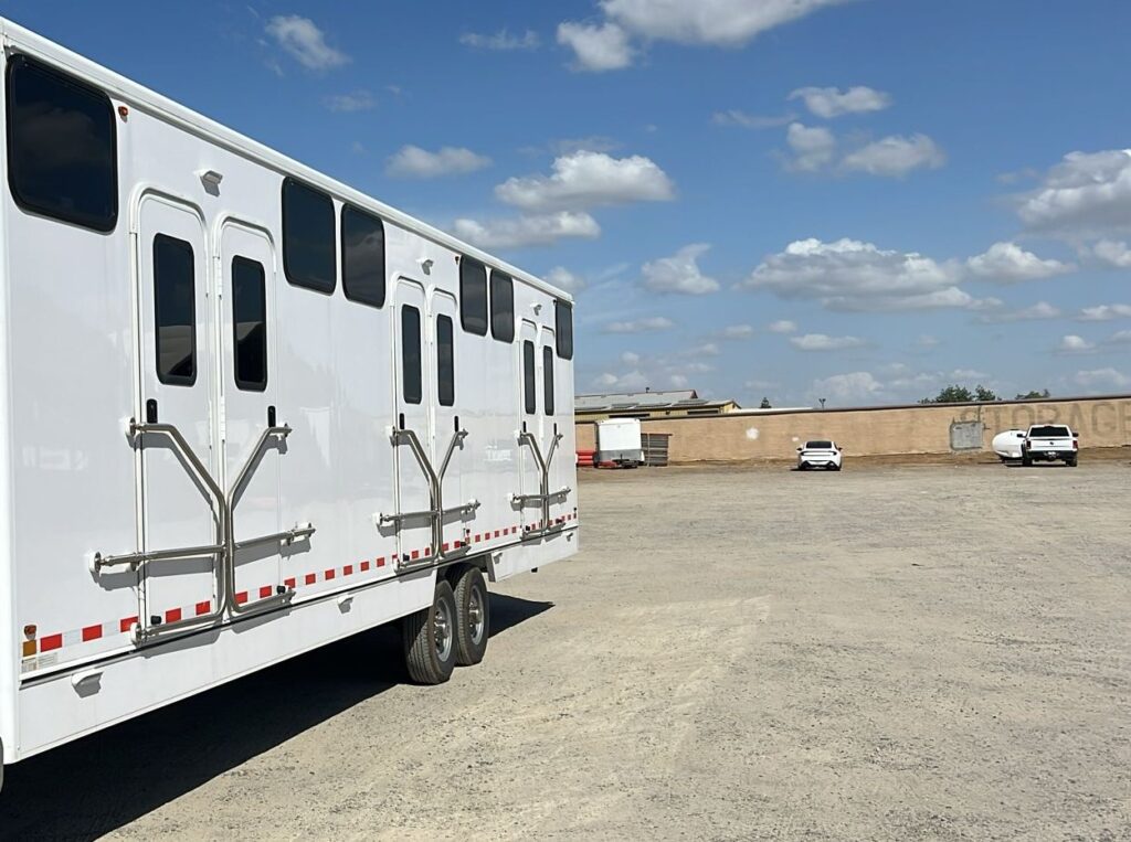 Mobile bunkhouse sleeper trailer with three pairs of bunk doors and grab rails parked in an open yard, The Lavatory Los Angeles