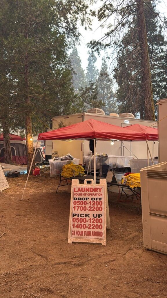Laundry drop-off and pick-up sign with a 24 hour turnaround in front of laundry tents at a forest camp, The Lavatory Los Angeles