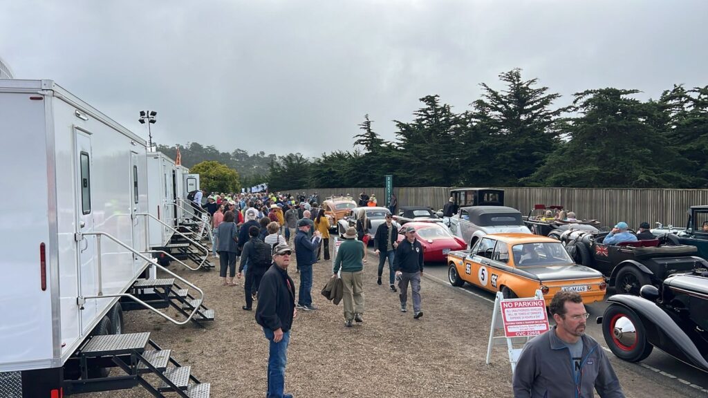 Large crowd of people walking past a row of luxury bathroom trailers at an outdoor car show, The Lavatory Los Angeles