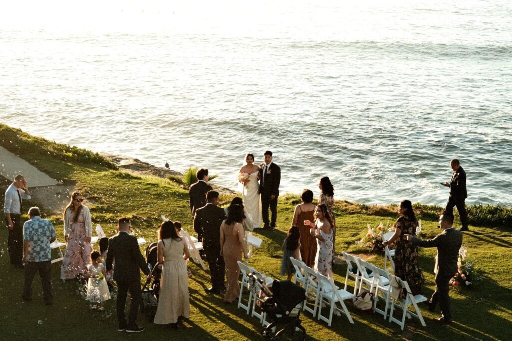 Wedding guests and the couple gathered on a grassy coastal bluff above the ocean after the ceremony, The Lavatory Los Angeles