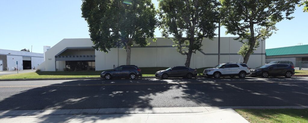 Tree-lined industrial building and parked cars on a west side business street in Garden Grove, CA, The Lavatory Los Angeles