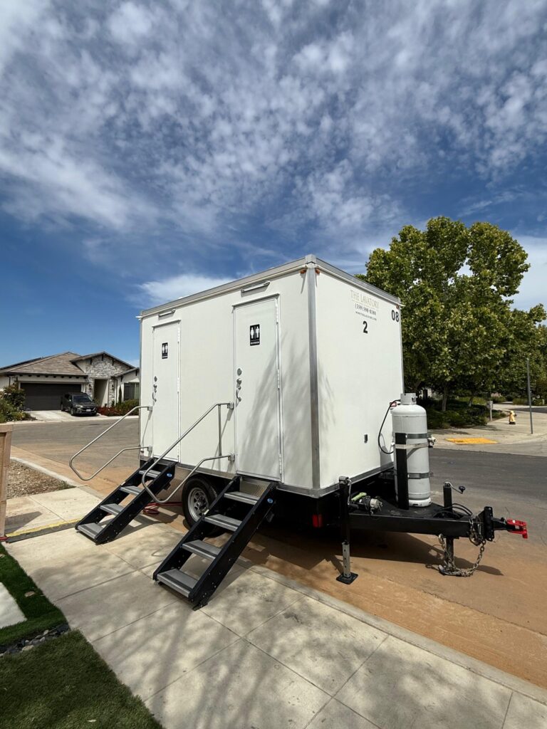 2-station bathroom trailer with steps on the sidewalk of a quiet residential street, The Lavatory Los Angeles