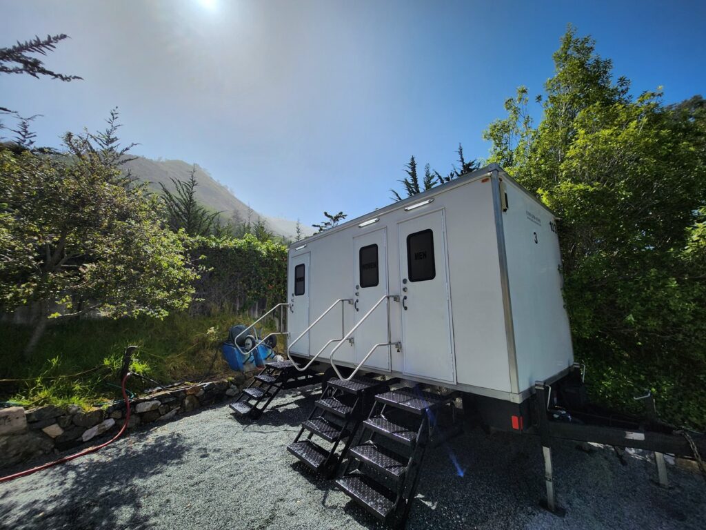 3-station bathroom trailer with three doors on a gravel pad at a hillside property, The Lavatory Los Angeles