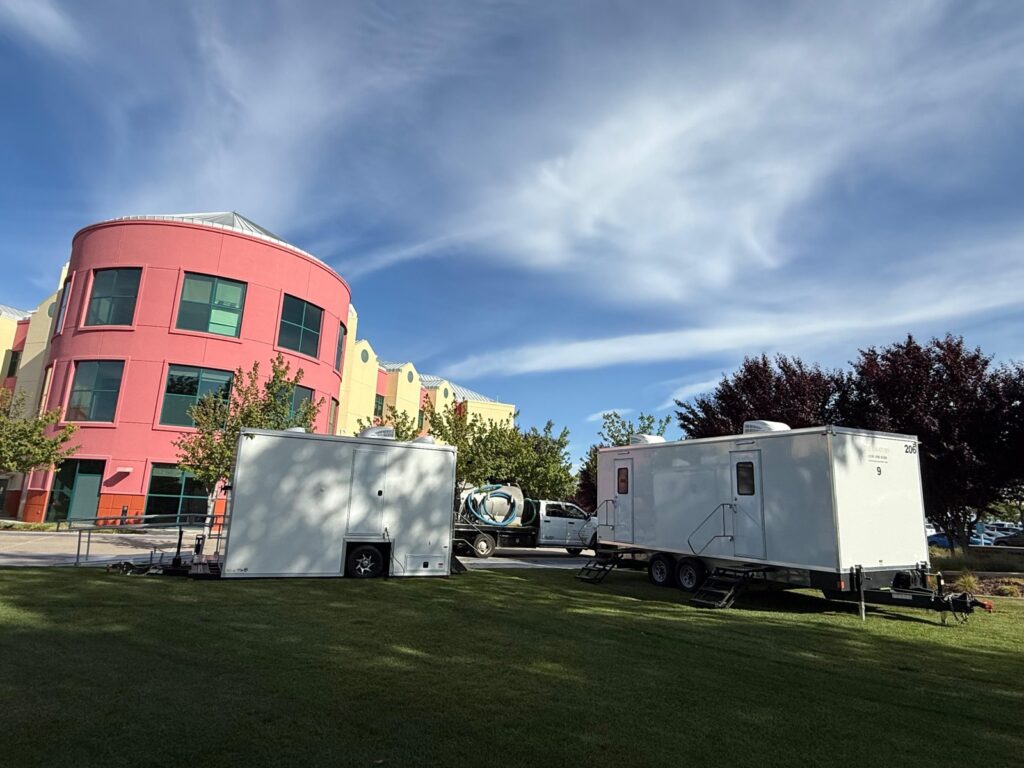ADA plus 2 and 9-station bathroom trailers on a hospital campus lawn, with our service crew pump truck parked between them, The Lavatory Los Angeles