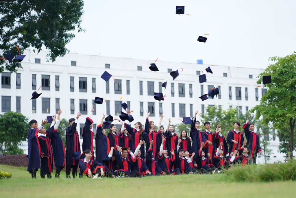 Graduates in gowns tossing their caps in the air on a campus lawn at a graduation party, The Lavatory Los Angeles