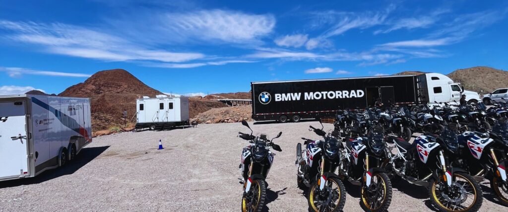 Portable bathroom trailers set up beside a BMW Motorrad truck and a lot of motorcycles at a brand event, The Lavatory Los Angeles