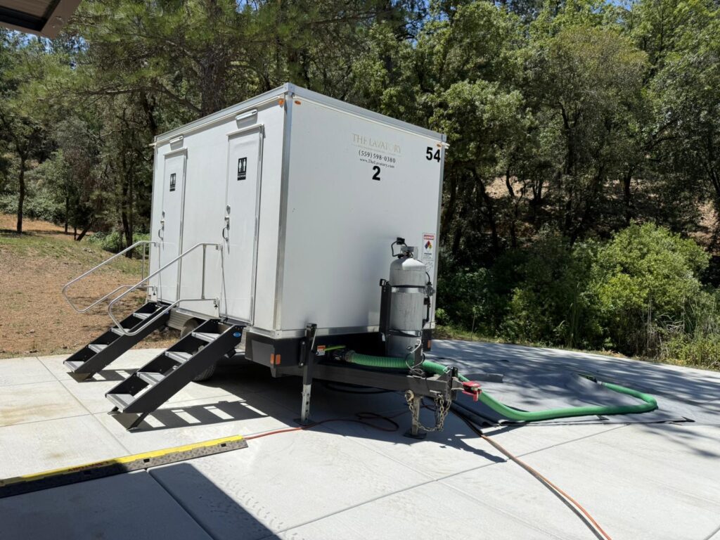 2-station combo trailer on a concrete pad with power cord and waste hose connected, The Lavatory Los Angeles