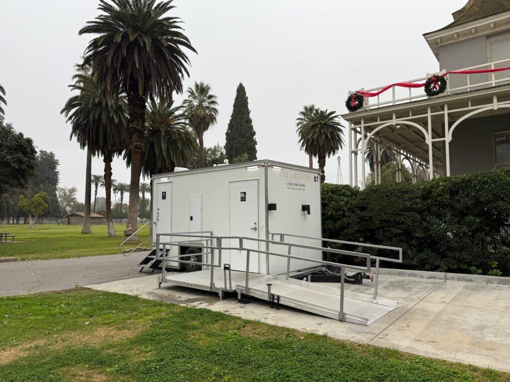 ADA plus 2 bathroom trailer with a ramp and landing beside a historic mansion and palm trees at a holiday event, The Lavatory Los Angeles