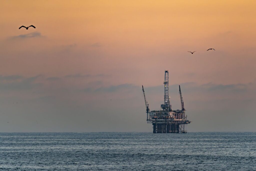 Offshore oil platform at sunset with pelicans flying over the water off Huntington Beach, The Lavatory Los Angeles