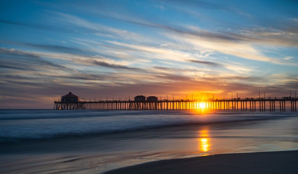Huntington Beach Pier at sunset with the sun setting between the pilings, The Lavatory Los Angeles