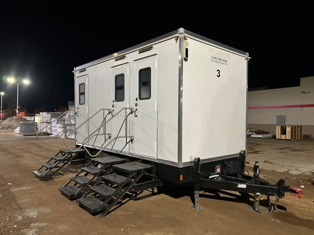 3-station bathroom trailer with three sets of steps lit up at night on a commercial job site, The Lavatory Los Angeles