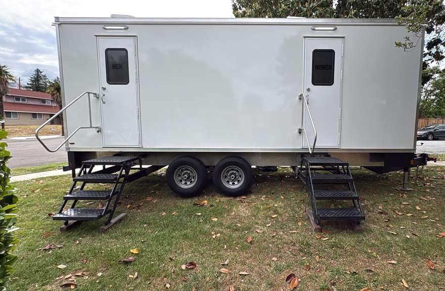 9-station bathroom trailer with separate women's and men's entrances and fold-down steps set up on a lawn, The Lavatory Los Angeles