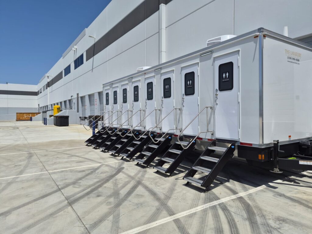 8-station private bathroom trailer with a stair at every stall door beside a new warehouse dock, The Lavatory Los Angeles