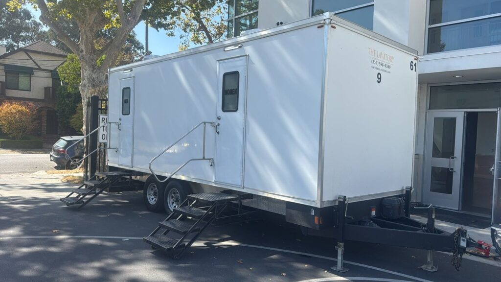 9-station bathroom trailer parked at the entrance of a modern office building, The Lavatory Los Angeles
