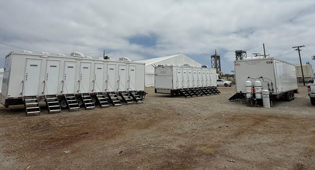Three 8-station private shower trailers set up on a dirt lot in Long Beach, The Lavatory Los Angeles