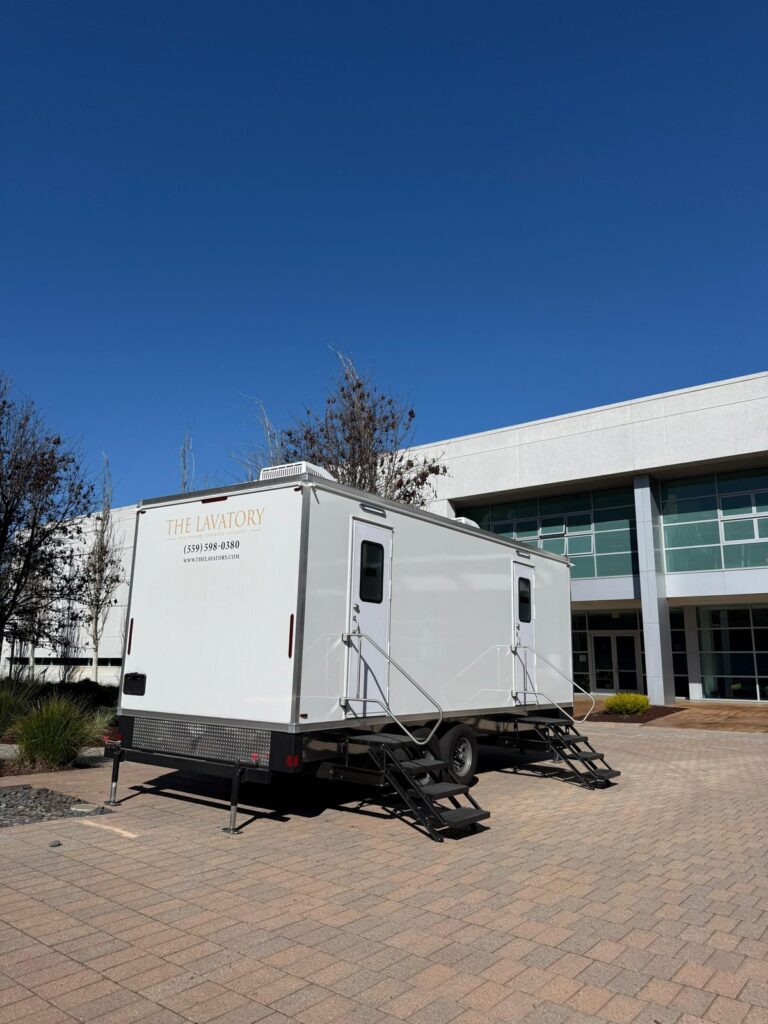 9-station bathroom trailer with steps at each door set on a brick plaza outside an office building, The Lavatory Los Angeles