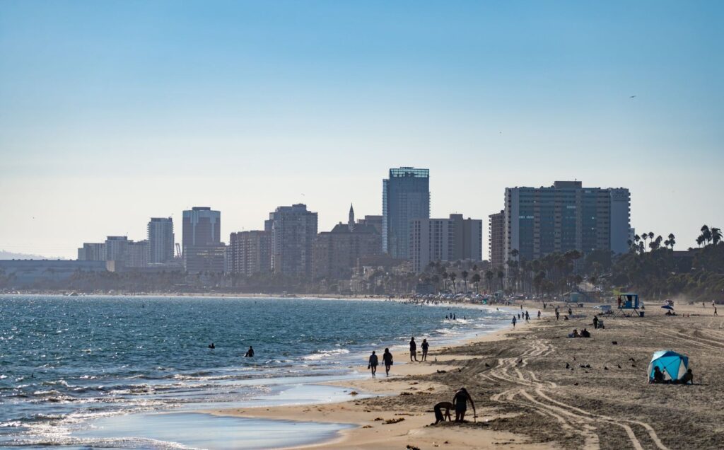 People walking the sand at Alamitos Beach with the Downtown Long Beach skyline behind them, The Lavatory Los Angeles