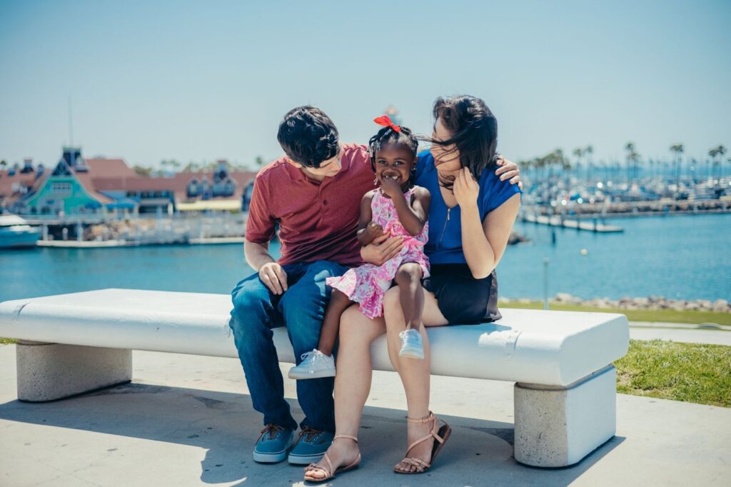 Family with a young child sitting on a bench by Rainbow Harbor in Long Beach, The Lavatory Los Angeles