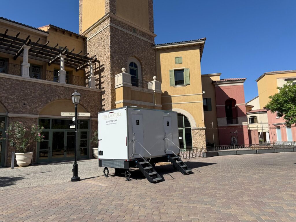 2-station bathroom trailer parked on a brick plaza in front of a Mediterranean style shopping courtyard, The Lavatory Los Angeles