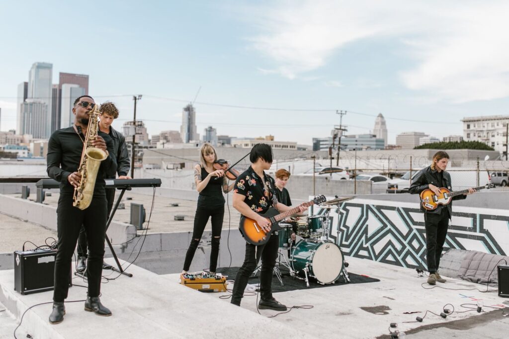 People playing in a band at a rooftop event with the Downtown Los Angeles skyline behind them, The Lavatory Los Angeles
