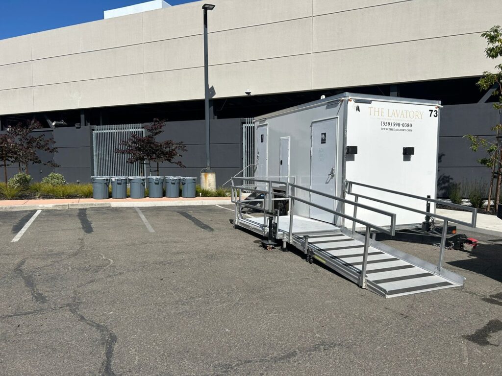 Three-room accessible bathroom trailer with a ramp and landing in an office building parking lot, The Lavatory Los Angeles