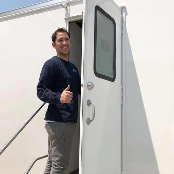 Smiling team member giving a thumbs up from a bathroom trailer doorway, The Lavatory Los Angeles