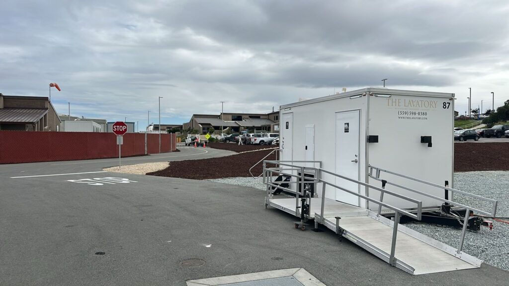 Accessible bathroom trailer with a ramp on gravel at a new campus construction site, The Lavatory Los Angeles