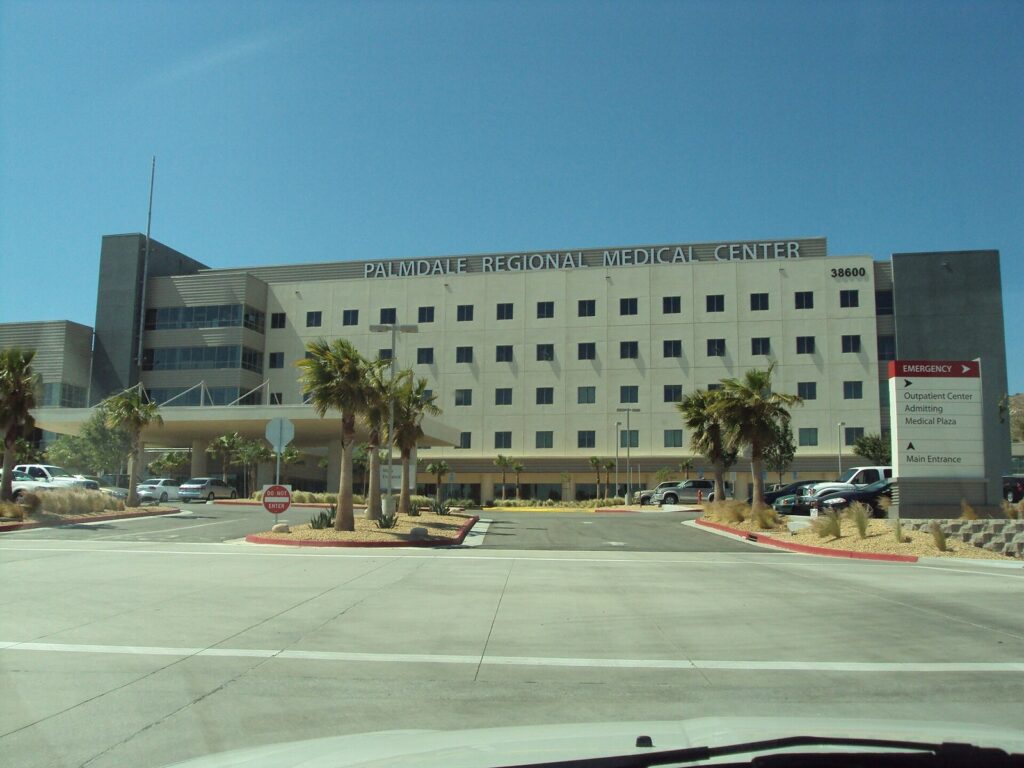 Palmdale Regional Medical Center main building with palm trees and the emergency entrance sign in Palmdale, CA, The Lavatory Los Angeles